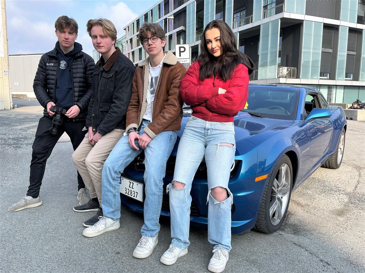 Fire ungdommer foran en blå Chevrolet Camaro. - Klikk for stort bilde