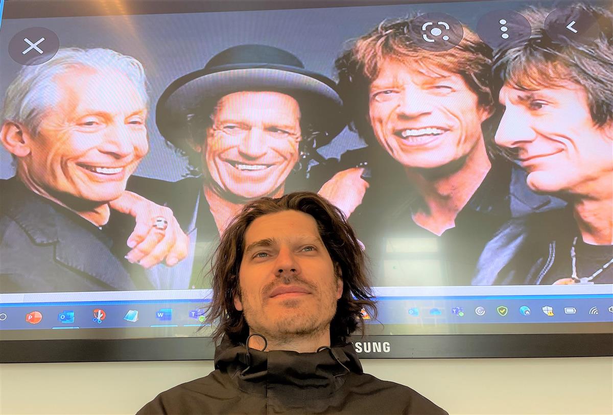 Yngre mann foran bilde av Rolling Stones - Klikk for stort bilde