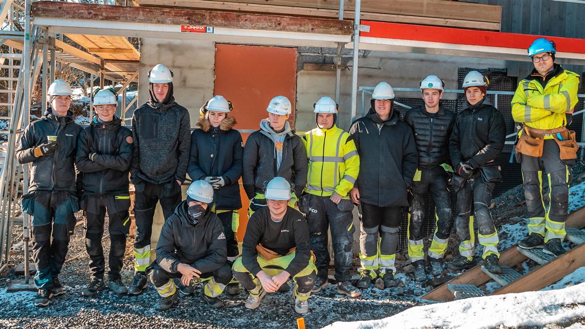 Gruppe av unge bygningsarbeidere foran nybygg - Klikk for stort bilde